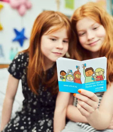 Children reading in the German Version of the Convention on the Rights of the Child. The photo was produced in the context of the campaign of the German Committee for UNICEF "Children's Rights into the Basic Law / Kinderrechte ins Grundgesetz".