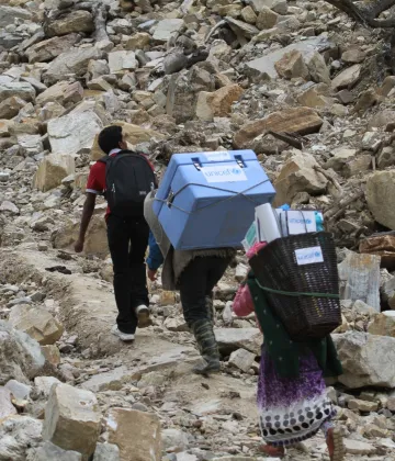 Porters and a local health official carry UNICEF-provided vaccines on difficult terrains on the way to a measles, rubella and polio vaccination campaign to be conducted at Barpak Village Development Committee (VDC) health post in Gorkha District, the epicentre of the April 25 earthquake.