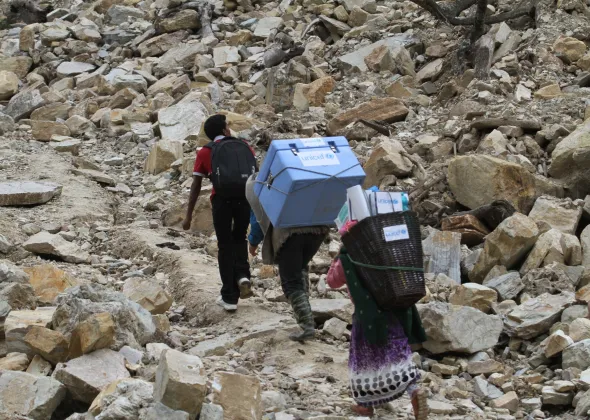 Porters and a local health official carry UNICEF-provided vaccines on difficult terrains on the way to a measles, rubella and polio vaccination campaign to be conducted at Barpak Village Development Committee (VDC) health post in Gorkha District, the epicentre of the April 25 earthquake.