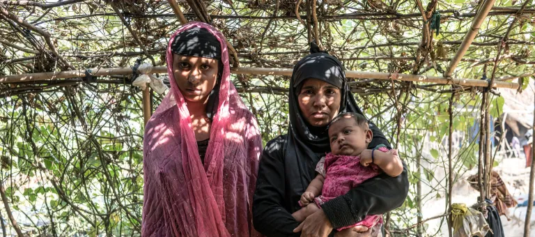 Rohingya refugee (left) Asmot Ara, 14, stands alongside her mother-in-law Laila, who is holding Asmot's two-month old baby Rubina, outside their tent in the Balukhali makeshift settlement, Cox's Bazar district, Bangladesh