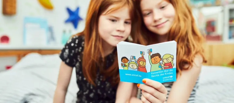 Children reading in the German Version of the Convention on the Rights of the Child. The photo was produced in the context of the campaign of the German Committee for UNICEF "Children's Rights into the Basic Law / Kinderrechte ins Grundgesetz".