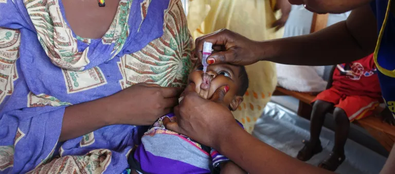 Sabir, 5 months, is administered an oral poliovirus vaccine (OPV), part of a routine immunization schedule, as he is held by his mother Rajak (left) at the IOM Health Clinic at the Wau Protection of Civilians (PoC) site adjacent to the UN Mission in South Sudan (UNMISS) base in Wau, South Sudan, Friday 7 April 2017. Sabir’s mother Rajak feels the PoC is the only place where they are safe from the recent violence around Wau town. Rajak and her eldest child arrived at the Wau PoC in June 2016 when fighting er