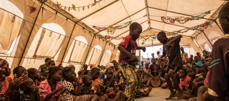 3 December 2019. Kaya, Burkina Faso. Children dance under a tent in the child friendly space set up by UNICEF, as part of activities to entertain the displaced children. The child friendly space is overcrowded, due to the increasing amount of displaced children coming everyday.