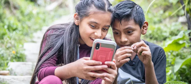 Een jongen en een meisjes kijken op hun telefoon in Solola, Guatemala