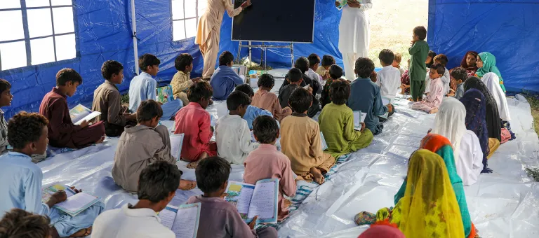 Meisjes en jongens gaan naar hun eerst les in een tijdelijk leercentrum dat door UNICEF werd opgezet voor kinderen die getroffen zijn door de overstromingen in Sindh, Pakistan. © UNICEF/UN0701749/Zaidi