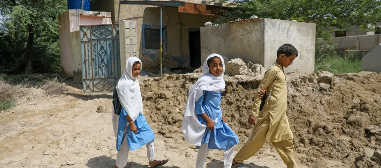 Meisjes en jongens komen voorbij hun school die helemaal verwoest werd door de overstromingen in Baluchistan, Pakistan. © UNICEF/UN0701846/Zaidi