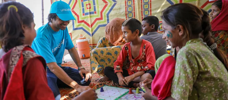 UNICEF-medewerker, Moeed Hussain, speelt bordspelletjes in een kindvriendelijke ruimte opgezet door UNICEF in een kamp opgezet door de overheid in Sindh, Pakistan. © UNICEF/UN0702949/Zaidi