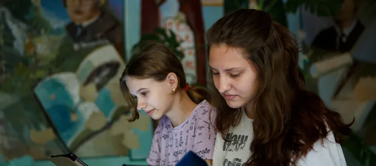 De 16-jarige Anastasiya uit Izyum, bij  Kharkiv in Oost-Oekraïne, (rechts) en de 13-jarige Kateryna uit Severodonetsk, een stad in Luhansk zijn aan het lezen op hun op tablet 