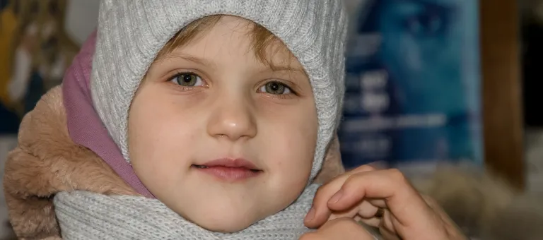 Ulyana, 5 jaar, trekt de nieuwe winterjas aan uit de winterkit die ze kreeg van UNICEF