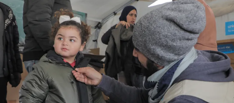 unicef staff gives warm clothes to a child
